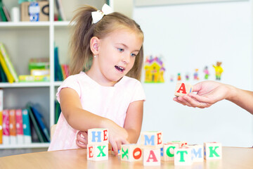 developmental and speech therapy classes with a child-girl. Speech therapy exercises and games with letters. dice game