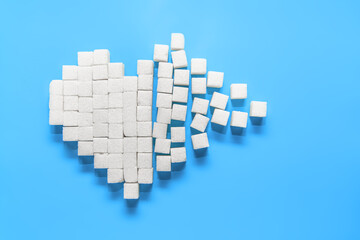Broken heart of pure white sugar cubes on a blue background, the world day of struggle against diabetes