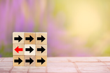 Wood block red arrow pointing the opposite way disruptive from the black arrows on table wooden....