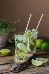 Glass of cucumber cocktail or mocktail, refreshing summer drink with crushed ice and sparkling water on a wooden background