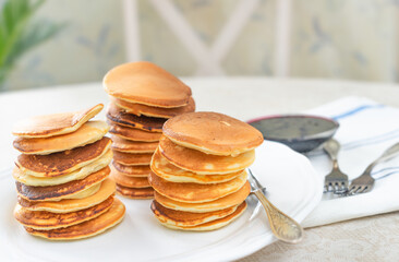 Breakfast is served with fresh, flavorful pancakes on a white plate and jam. Close-up, selective focus, light background