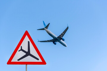Airplane during take off and road airplane traffic sign, attention sign with plane, low flying aircraft.