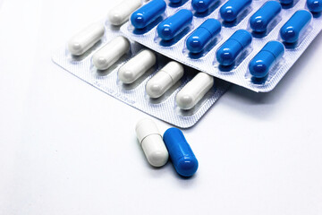 Close up a supplements medicine capsules of white and blue colors against white background
