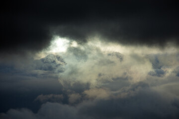 Naklejka na ściany i meble Sun shining through dark clouds.
