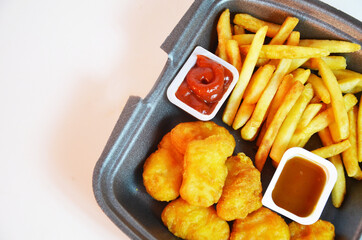 Yummy French fries, chicken Nuggets, sauce, paper bag, white background. Binge eating. food delivery
