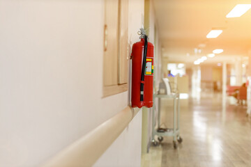 Fire extinguisher in the operating department . Install a fire extinguisher on the wall in building. Dry chemical powder fire extinguisher in corridor .a red fire-extinguisher hangs on wall . - obrazy, fototapety, plakaty