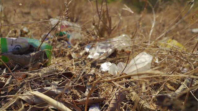 Plastic Trush on the Ground Surrounded by Dry Leaves and Grass