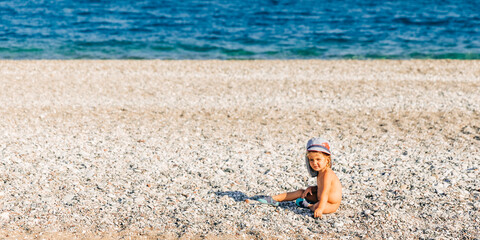 Fototapeta na wymiar Lonely toddler girl sitting on beach