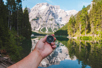 Fototapeta na wymiar hand holding compass view of mountain lake on background