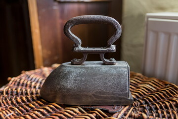 Old time flat iron appliance with standing on a wicker basket