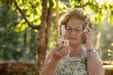 senior woman with mobile phone and headphones outdoors