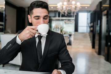 Businessman drinking coffee at hotel lobby.