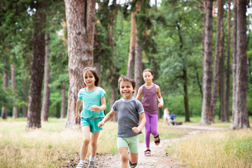 Three happy children running in forest