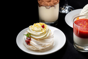 Pavlova meringue cake with fresh berries on black background.