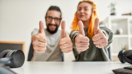 Cheerful man and woman showing thumbs up at camera. Young male and female technology blogger recording video blog or vlog about new gadgets at home