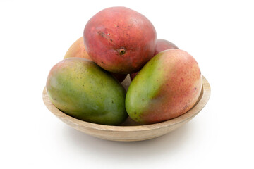 Tres mangos en un cuenco de madera sobre fondo blanco.