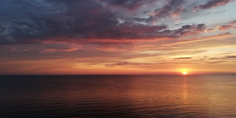 Bright dramatic sea sunset landscape in golden and grey colors. Autumn sunset in the sky of amazing beauty.The sea horizon is hidden in a dark haze. Halloween background 