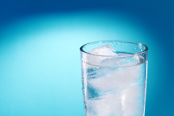 fresh ice water glass close up over blue background. copy space. ice drink at summer season. refreshment beverage. healthy lifestyle concept