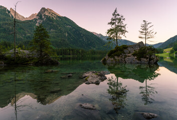 Beautiful scene of trees on a rock island and mountains at sunset time in summer, Lake Hintersee National park Berchtesgadener Land, Upper Bavaria, Germany, Europe