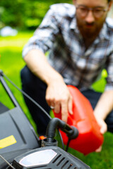 Fototapeta na wymiar Refilling the fuel tank in a petrol lawn mower. Gardening, mowing with a gasoline lawnmower.