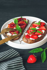 Tasty sandwiches with strawberry, blood orange, soft cheese and basil leaves on roasted wholegrain bread. Healthy delicious breakfast or lunch concept.