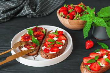 Tasty sandwiches with strawberry, blood orange, soft cheese and basil leaves on roasted wholegrain bread. Healthy delicious breakfast or lunch concept.