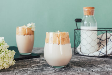 Two glasses of tasty fresh Dalgona coffee. Trendy Korean drink with instant coffee decorated with hydrangea flowers