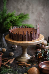 Chocolate cheesecake on a large wooden cake plate. Decorated with chocolate pieces. New Year's table decoration. Festive sweets.