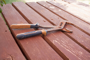 Large rusty pliers with plastic handles on a background of brown old wooden planks.