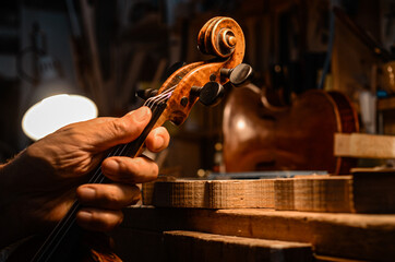 Luthier violin maker artisan setting up a violin in his workshop