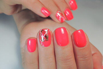Hands of a young woman. Close-up of nails covered with red gel Polish, abstract design with foil. Manicure.