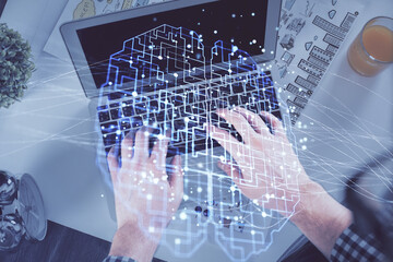 Double exposure of man's hands typing over computer keyboard and brain hologram drawing. Top view. Ai and data technology concept.