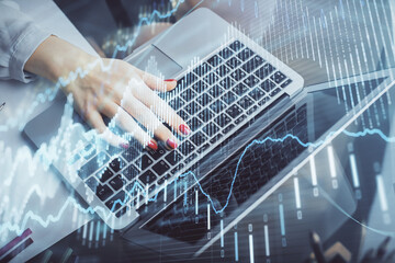 Double exposure of businesswoman hands typing on computer and financial graph hologram drawing. Stock market analysis concept.