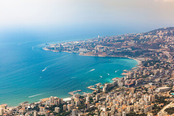 Obraz premium Aerial view of the Jounieh coastal city, Lebanon. Panoramic view of the seaside resorts, turquoise sea water, boats, paragliders, buildings