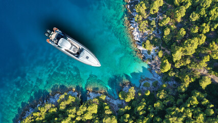 Aerial drone top down photo of inflatable speed boat anchored in tropical exotic island covered...