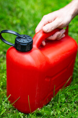 Red plastic fuel canister for a petrol lawn mower. Gardening, mowing with a gasoline lawnmower.