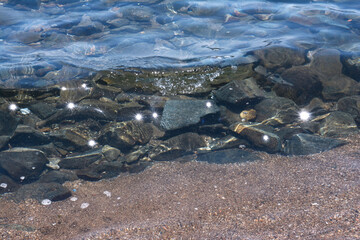 Texture of water. Abstract image of top view of shiny wave of clear sea water over sand beach, for beautiful background decoration of summer time. Game of light on the sea, sand beach . sea urchins.