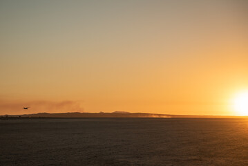 Fototapeta premium Flying private plane about to land toward the sun in the desert during sunset