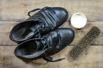 old leather shoes with shoe polish and  brushes against aged cracked wooden boards