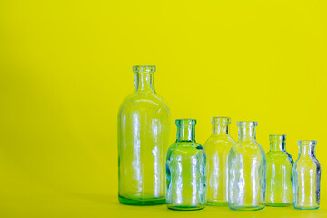six empty glass bottles of different sizes on the yellow background. Concept of medicine and science.