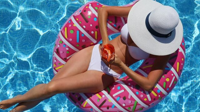 Young relaxed woman in a swimsuit in the water on an inflatable donut ring. View from above.