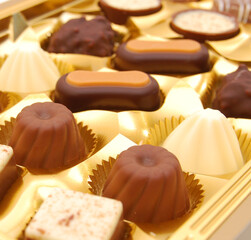 many chocolate appetizing candys with icing in golden box