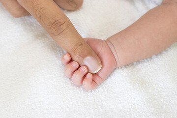 ３０代の父親の指を握りしめる、生後一ヶ月の赤ちゃんの手