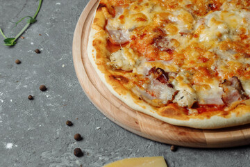 pizza with cheese, sauce and ham, bacon, salami on a gray dark background