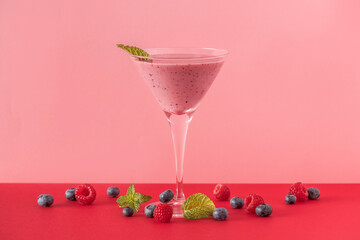 Berry smoothie cup with several blueberries and raspberries on a red and pink background.