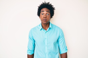 Handsome african american man with afro hair wearing casual clothes puffing cheeks with funny face. mouth inflated with air, crazy expression.