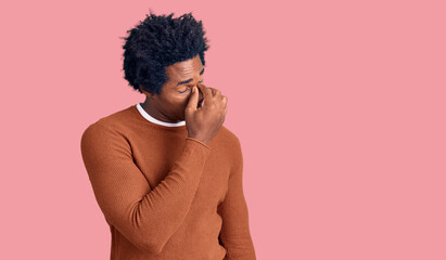 Handsome african american man with afro hair wearing casual clothes tired rubbing nose and eyes feeling fatigue and headache. stress and frustration concept.