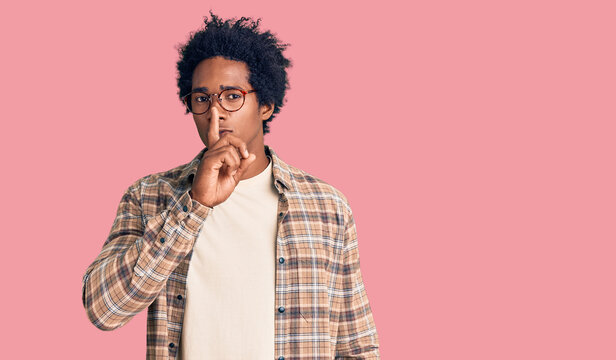 Handsome african american man with afro hair wearing casual clothes and glasses asking to be quiet with finger on lips. silence and secret concept.