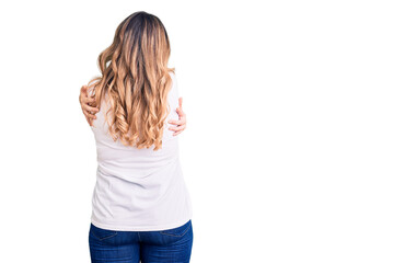 Young caucasian woman wearing casual clothes hugging oneself happy and positive from backwards....