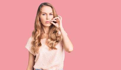 Fototapeta premium Young beautiful caucasian woman with blond hair wearing casual clothes mouth and lips shut as zip with fingers. secret and silent, taboo talking